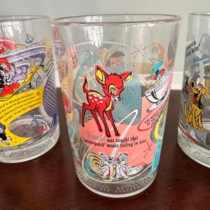Op de afbeelding: Een helder drinkglas met een kleurrijke afbeelding van Bambi, Knabbel en Babbel, en de tekst: Bambi was taught that twitterpated meant falling in love. Het ontwerp bevat sterren in mid-century stijl en een roze cirkelvormig accent.