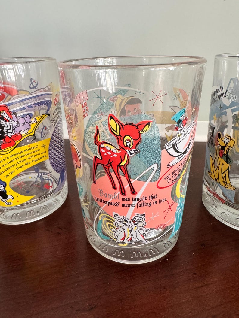Op de afbeelding: Een helder drinkglas met een kleurrijke afbeelding van Bambi, Knabbel en Babbel, en de tekst: Bambi was taught that twitterpated meant falling in love. Het ontwerp bevat sterren in mid-century stijl en een roze cirkelvormig accent.