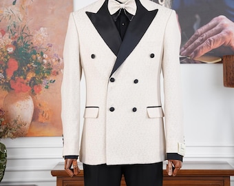 Puede incluir: Un traje de doble botonadura color crema con solapas y botones negros, combinado con pantalones negros y una pajarita a juego. El traje se exhibe en un maniquí, mostrando un conjunto de vestimenta formal.