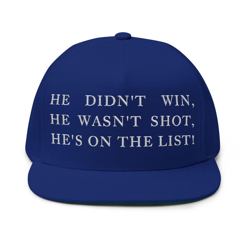 Puede incluir: Gorra de b&eacute;isbol azul real con visera plana. La gorra tiene texto bordado en blanco: "HE DIDN'T WIN, HE WASN'T SHOT, HE'S ON THE LIST!" La parte inferior de la visera es verde.