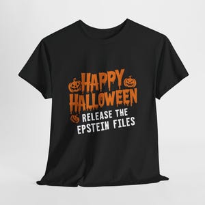 Puede incluir: Camiseta negra con texto naranja "HAPPY HALLOWEEN" sobre "RELEASE THE EPSTEIN FILES". El diseño incluye gráficos de calabazas. Una camiseta gráfica con temática de Halloween.