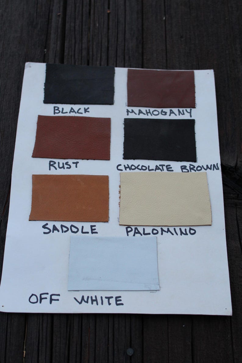 K&ouml;nnte beinhalten: Eine wei&szlig;e Karte mit Lederproben in verschiedenen Farben, darunter Schwarz, Mahagoni, Rost, Schokoladenbraun, Sattel, Palomino und Off-White. Die Farben sind unter jeder Probe beschriftet.