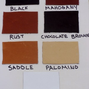 May include: A color swatch card displaying samples of leather in various shades. The colors include black, mahogany, rust, chocolate brown, saddle, palomino, and white. Each swatch is labeled with its corresponding color name in black ink.