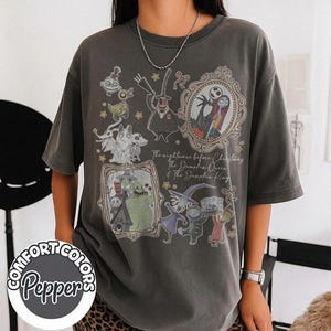 May include: A charcoal gray short-sleeve t-shirt featuring a graphic print of characters from The Nightmare Before Christmas, including Jack Skellington, Sally, and Oogie Boogie, with the text The Nightmare Before Christmas The Pumpkin Queen & The Pumpkin King.