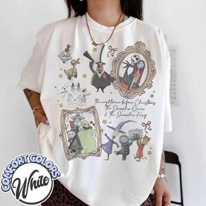 May include: An off-white t-shirt featuring a graphic print of characters from The Nightmare Before Christmas, including Jack Skellington, Sally, and Oogie Boogie, with the text The Nightmare Before Christmas, The Pumpkin Queen & The Pumpkin King.