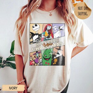 May include: An ivory short-sleeve t-shirt featuring a multi-panel graphic print of characters from The Nightmare Before Christmas. The design includes Jack Skellington, Sally, Zero, and other figures with the text Nightmare Before Christmas.