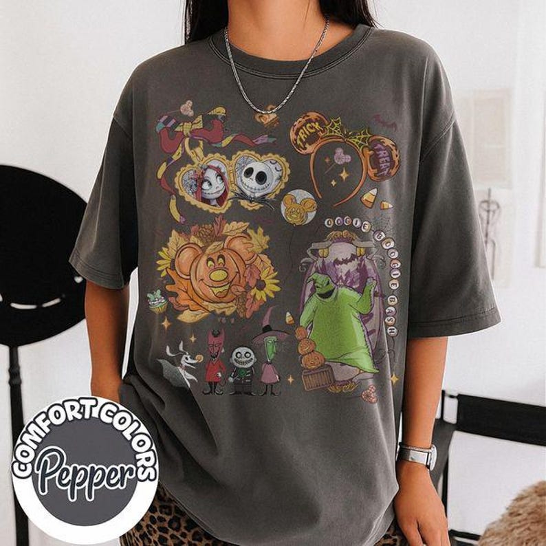 Pode incluir: Uma t-shirt de manga curta cinzento-carv&atilde;o com uma impress&atilde;o gr&aacute;fica de personagens de O Estranho Mundo de Jack, incluindo Jack Skellington, Sally e Oogie Boogie, juntamente com &iacute;cones de outono como ab&oacute;boras e doces de milho.