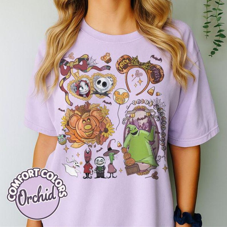 Pode incluir: Uma t-shirt roxo-claro com uma estampa gr&aacute;fica de personagens e &iacute;cones de O Estranho Mundo de Jack, incluindo Jack Skellington, Sally, Oogie Boogie e Zero, rodeados por folhas de outono, doces de milho e tiaras de orelhas de rato.