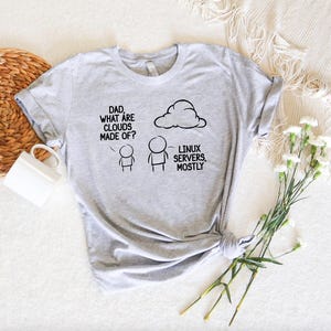 May include: A gray t-shirt with a humorous illustration of a child asking "Dad, what are clouds made of?" and an adult pointing to a cloud with the text "Linux servers, mostly."