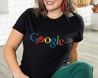 May include: Black t-shirt with the word "Google" in the Google logo colors: blue, red, yellow, and green. The word "IT" is in red, replacing the "o" in Google. The shirt is worn with green pants.
