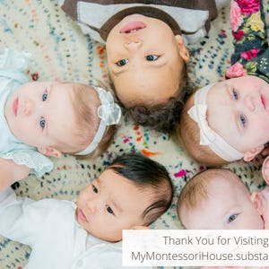 May include: Five babies lie on a patterned blanket, looking up at the camera.  The babies are of different ethnicities and have different hair colors.  The babies are wearing various outfits, including a white onesie, a pink onesie, a blue onesie, a white dress, and a black and white patterned dress.  The blanket is a light beige color with a multi-colored pattern.