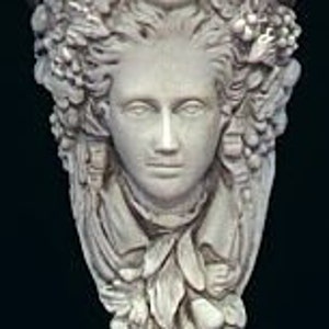 May include: A white plaster wall shelf with a sculpted female face surrounded by grapes, leaves, and fruit. The shelf is designed in a traditional style.