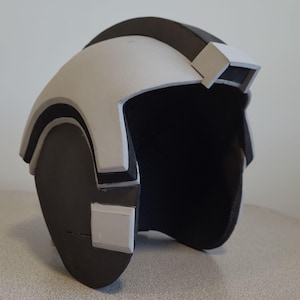 May include: A white and black helmet with a visor. The helmet is made of foam and has a textured surface.