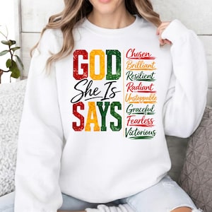 May include: White sweatshirt with the text "GOD She Is SAYS" in red, yellow, and green. The right side features a list of words: Chosen, Brilliant, Resilient, Radiant, Unstoppable, Graceful, Fearless, and Victorious.
