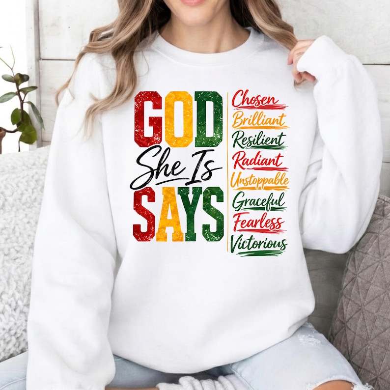 May include: White sweatshirt with the text "GOD She Is SAYS" in red, yellow, and green. The right side features a list of words: Chosen, Brilliant, Resilient, Radiant, Unstoppable, Graceful, Fearless, and Victorious.