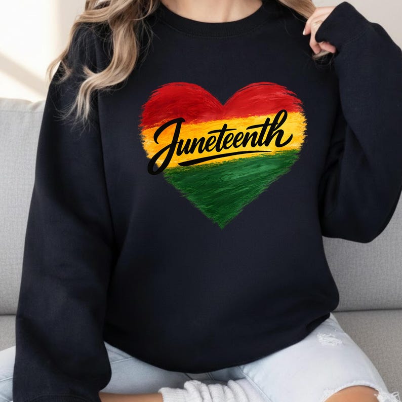 May include: Black sweatshirt with a heart-shaped design in red, yellow, and green. The word "Juneteenth" is written in a cursive font across the heart.