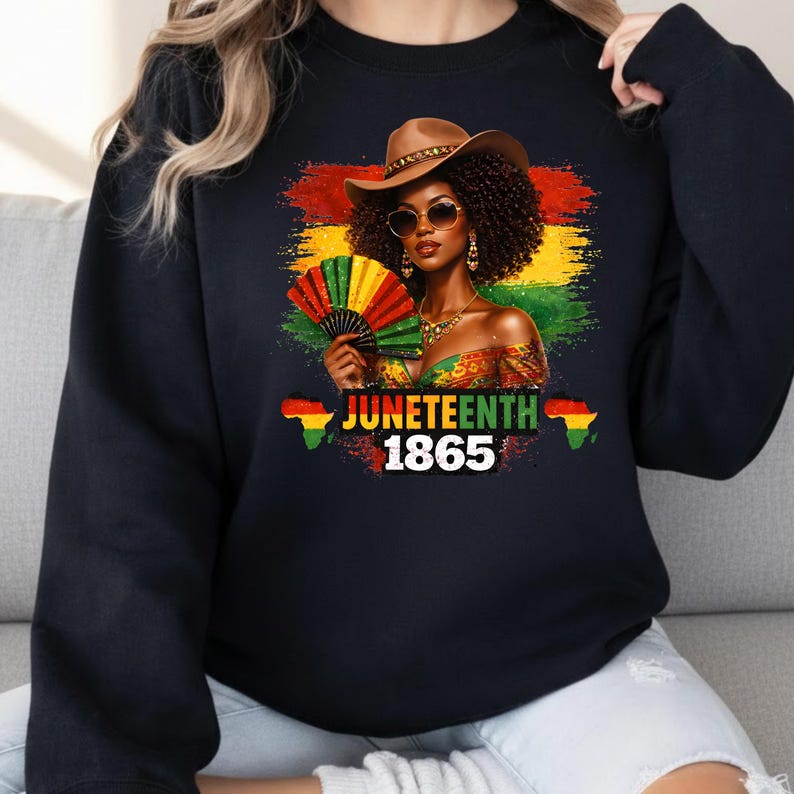 May include: Black sweatshirt with a graphic of a woman in a cowboy hat and sunglasses, holding a fan. The design includes the text "Juneteenth 1865" with the Pan-African flag colours and African continent outlines.