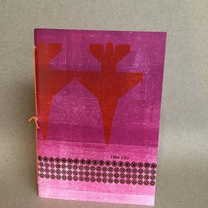以下が含まれることがあります： ピンクと赤のカードに、赤い飛行機のグラフィックが描かれています。カードは黒い縁取りがされており、円が繰り返し描かれた模様になっています。カードには「I like you」という文字が印刷されています。