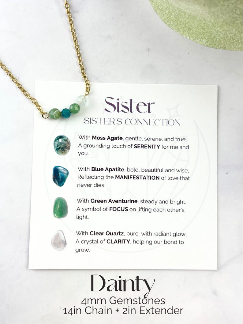 Może przedstawiać: Złoty naszyjnik z kartą, na kt&oacute;rej napisano "Siostra, Połączenie si&oacute;str". Karta opisuje znaczenie każdego kamienia szlachetnego: agatu mchowego, apatytu niebieskiego, awenturynu zielonego i czystego kwarcu. Naszyjnik ma długość 35,5 cm z przedłużką 5 cm i zawiera kamienie szlachetne o średnicy 4 mm. Na karcie widnieje r&oacute;wnież napis "Delikatny, Kamienie szlachetne 4 mm, Łańcuszek 35,5 cm + przedłużka 5 cm".