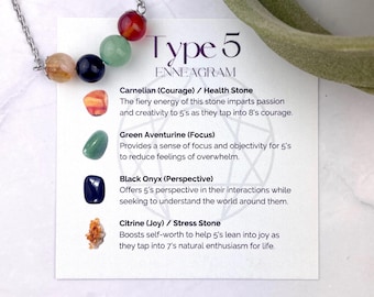 May include: A silver-toned chain necklace featuring four small, round, polished gemstone beads in red, green, black, and yellow. The necklace rests on a white card printed with the text Type 5 ENNEAGRAM and descriptions of Carnelian, Green Aventurine, Black Onyx, and Citrine stones.