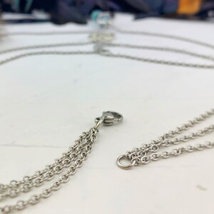Pu&ograve; includere: Collana a catena color argento con pi&ugrave; fili. La collana presenta un design delicato con piccole maglie a catena. La chiusura &egrave; visibile e la collana sembra essere in metallo.