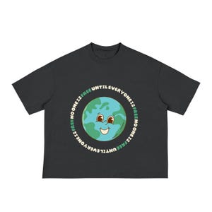 May include: Dark grey t-shirt with a smiling Earth graphic and the text "UNTIL EVERYONE IS FREE NO ONE IS FREE" in a circular design. The Earth graphic is in shades of blue and green.