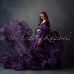 May include: A flowing, deep purple maternity gown with ruffled details and a high slit. The gown is worn by a person with long brown hair, and the text "In The Lens by Kaminski" is visible.