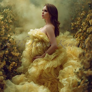 May include: A woman wearing a strapless, yellow ruffled gown. The dress has a layered, voluminous design. The background shows soft lighting and foliage, with the text "The Lost of Kami" visible.
