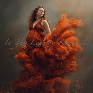 Puede incluir: Un vestido de maternidad naranja con cuello halter y corpiño detallado. El vestido presenta capas de tela con volantes que ondean alrededor de la figura. La imagen incluye el texto "In The Lens by K".