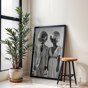 May include: A black and white photograph of a couple wearing disco ball headpieces. The couple is standing in front of a white background. The photo is framed in a black frame.