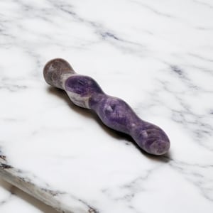 May include: A purple and white marbled stone sex toy with a curved design. The polished surface reflects light, highlighting the natural patterns. The toy is approximately 18 cm long. The color is a mix of purple and white.