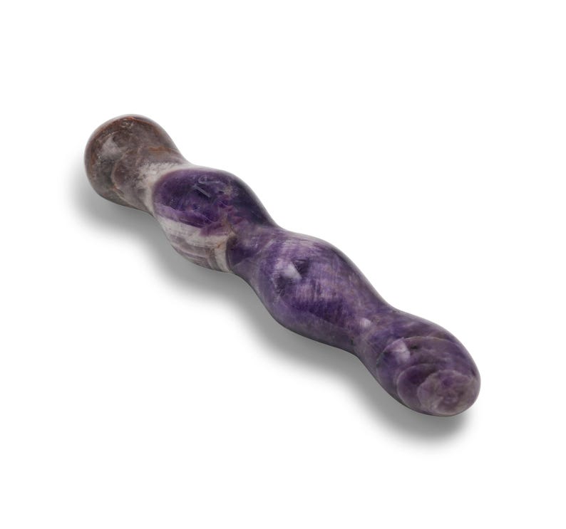 May include: A purple and white amethyst wand with a smooth, curved design. The wand is a natural stone with varying shades of purple and white, and is designed with a rounded tip and a curved shape.