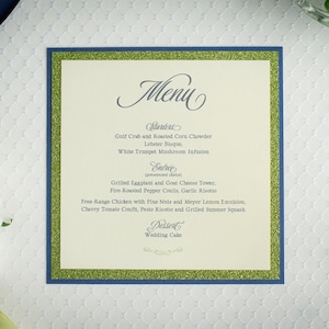 May include: A wedding menu card with a green glitter border and blue trim. The menu includes starters, entree, and dessert options. The text reads: "Menu", "Starters", "Gulf Crab and Roasted Corn Chowder", "Lobster Bisque", "White Trumpet Mushroom Infusion", "Entree", "Grilled Eggplant and Goat Cheese Tower", "Fire Roasted Pepper Coulls, Garlic Risotto", "Free Range Chicken with Pine Nuts and Meyer Lemon Emulsion", "Cherry Tomato Confit, Peste Risotto and Grilled Summer Squash", "Dessert", "Wedding Cake".