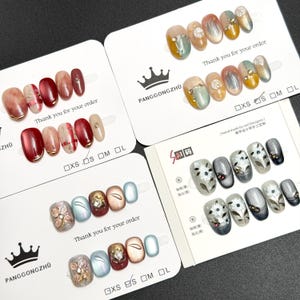 May include: Assorted sets of artificial nails in various designs. Some nails feature gold accents, floral patterns, and glitter. Each set is displayed on a white card with the text "Thank you for your order" and size labels.