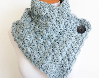 May include: A light blue crocheted cowl with a single black button on the side.