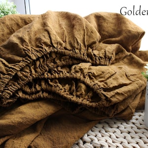 May include: A golden brown fitted sheet with elastic edges, made of a textured fabric. The sheet is crumpled, suggesting it is new or recently used. The words "Golden brown" are written in the top right corner.