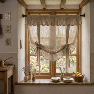 May include: A beige linen window curtain featuring a ruffled top header and two tie-up panels that create a draped, scalloped bottom edge. The curtain is suspended from a black rod and hangs over a wooden window frame with a visible weave texture.