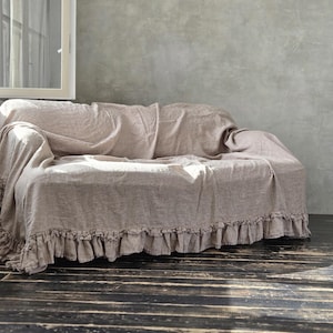 Peut inclure: Une housse de canap&eacute; en lin beige avec une finition en tissu textur&eacute; et un bord &agrave; volants d&eacute;coratif le long de la base. La housse recouvre le dossier, l'assise et les accoudoirs du canap&eacute;, offrant un aspect couvrant avec des plis souples.