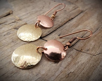 May include: A pair of dangle earrings with two round discs on each earring. The top disc is copper and the bottom disc is gold. Both discs have a hammered texture.