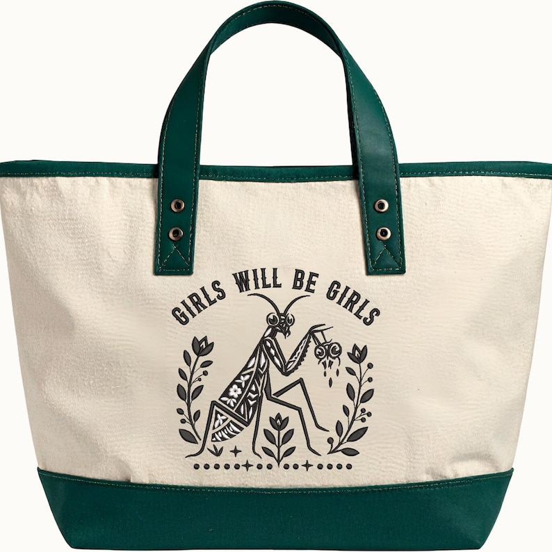 May include: A cream-colored canvas tote bag with dark green trim and handles. The front features a black graphic print of a praying mantis surrounded by floral elements and the text "GIRLS WILL BE GIRLS" arched above the insect illustration.