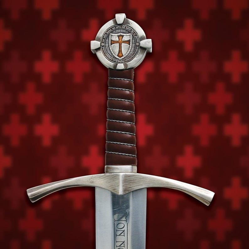 May include: A medieval sword with a silver blade and guard, and a brown leather-wrapped handle. The pommel features a circular design with a cross emblem. The background is a pattern of red crosses.