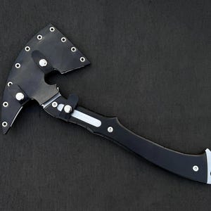 Peut inclure: Une hache noire avec un manche incurv&eacute; et une lame argent&eacute;e. La t&ecirc;te de la hache est recouverte d'un &eacute;tui en cuir noir fix&eacute; avec des rivets argent&eacute;s. La poign&eacute;e a un accent argent&eacute;.