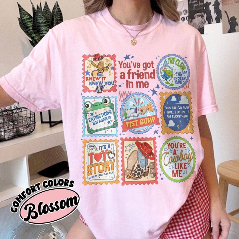 Puede incluir: Una camiseta rosa claro con una cuadr&iacute;cula de sellos gr&aacute;ficos coloridos con varias ilustraciones y textos, incluyendo You've got a friend in me, The Claw, Extinction Not Again, Fist Bump, Toys are for play, It's a Toy Story y You're a cowboy like me.