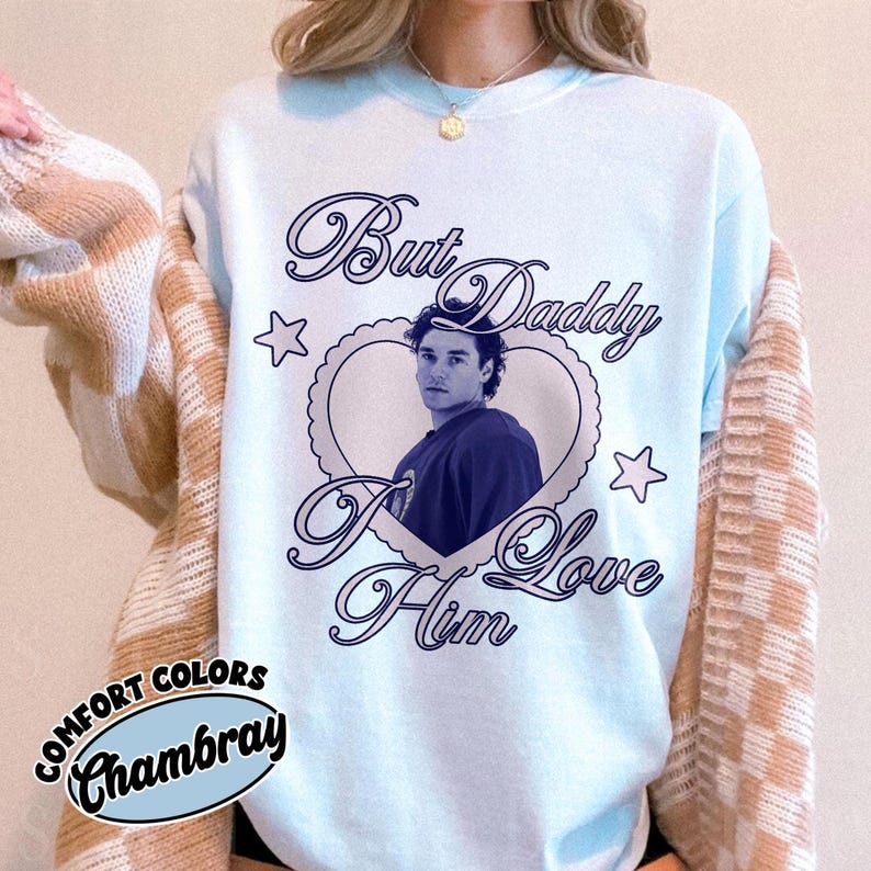 May include: Light blue Comfort Colors Chambray sweatshirt with the text "But Daddy I Love Him" in navy blue script. The design includes a heart-shaped frame with a photo and stars.
