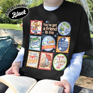 Puede incluir: Una camiseta negra con una cuadr&iacute;cula de parches gr&aacute;ficos coloridos con varias ilustraciones y textos, incluyendo You've got a friend in me, The Claw, Extinction Not Again, Fist Bump, It's a Toy Story y You're a Cowboy Like Me.