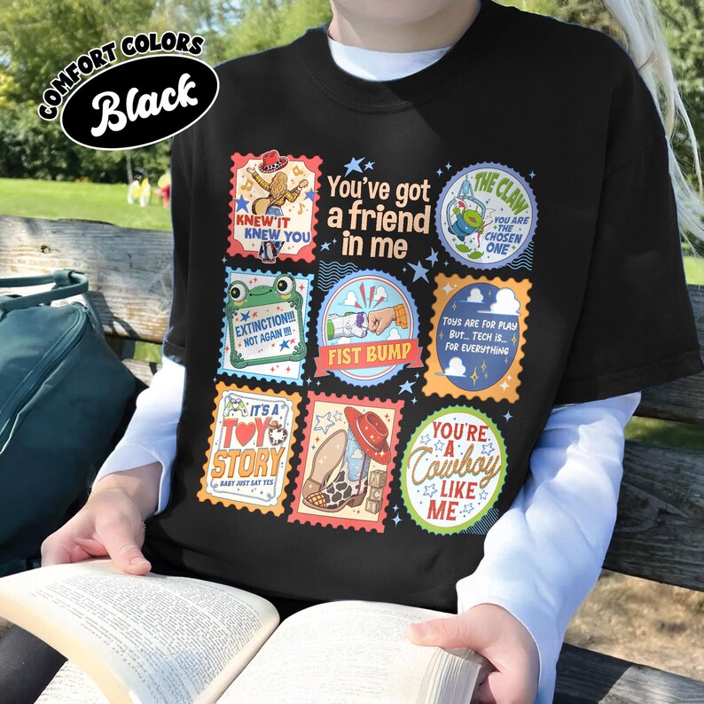 Puede incluir: Una camiseta negra con una cuadr&iacute;cula de parches gr&aacute;ficos coloridos con varias ilustraciones y textos, incluyendo You've got a friend in me, The Claw, Extinction Not Again, Fist Bump, It's a Toy Story y You're a Cowboy Like Me.
