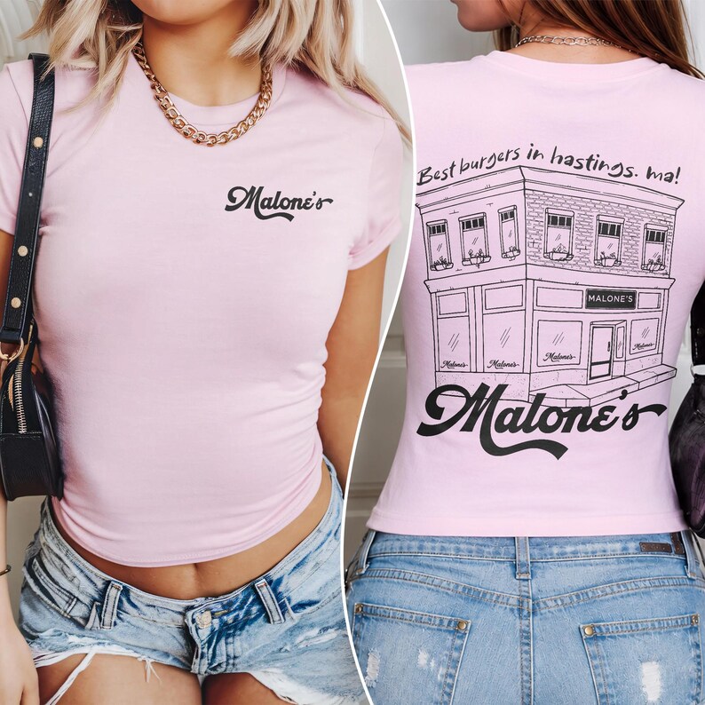 May include: A light pink short-sleeve t-shirt featuring the black text Malone's on the front chest. The back displays a black line-art illustration of a building with the text Best burgers in hastings. ma! and the script logo Malone's.