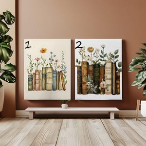 Puede incluir: Dos impresiones artísticas en lienzo con ilustraciones de acuarela de libros con flores. Una impresión tiene un fondo crema con flores y libros coloridos. La otra impresión tiene un fondo blanco con flores y libros en tonos marrones y verdes.