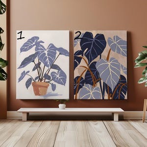 Puede incluir: Dos impresiones enmarcadas de ilustraciones botánicas abstractas azules y blancas. La impresión de la izquierda muestra una sola planta en una maceta. La impresión de la derecha muestra un grupo de hojas. Ambas impresiones tienen los números "1" y "2" escritos en ellas.