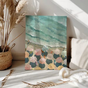 May include: An artistic canvas print depicts a beach scene from a high angle. The artwork showcases the ocean's turquoise waves meeting a sandy shore dotted with colorful beach umbrellas. The umbrellas are in shades of pink, yellow, and blue.